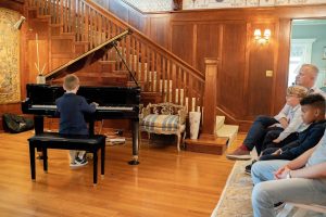 people watching a child at his in home piano concert in LA